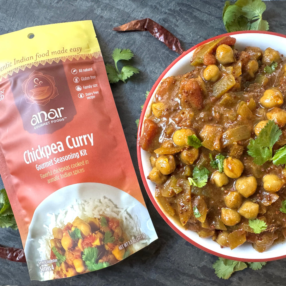 Anar Gourmet Foods all natural, gluten-free chickpea curry seasoning packet beside a bowl of prepared chickpea curry with cilantro garnish
