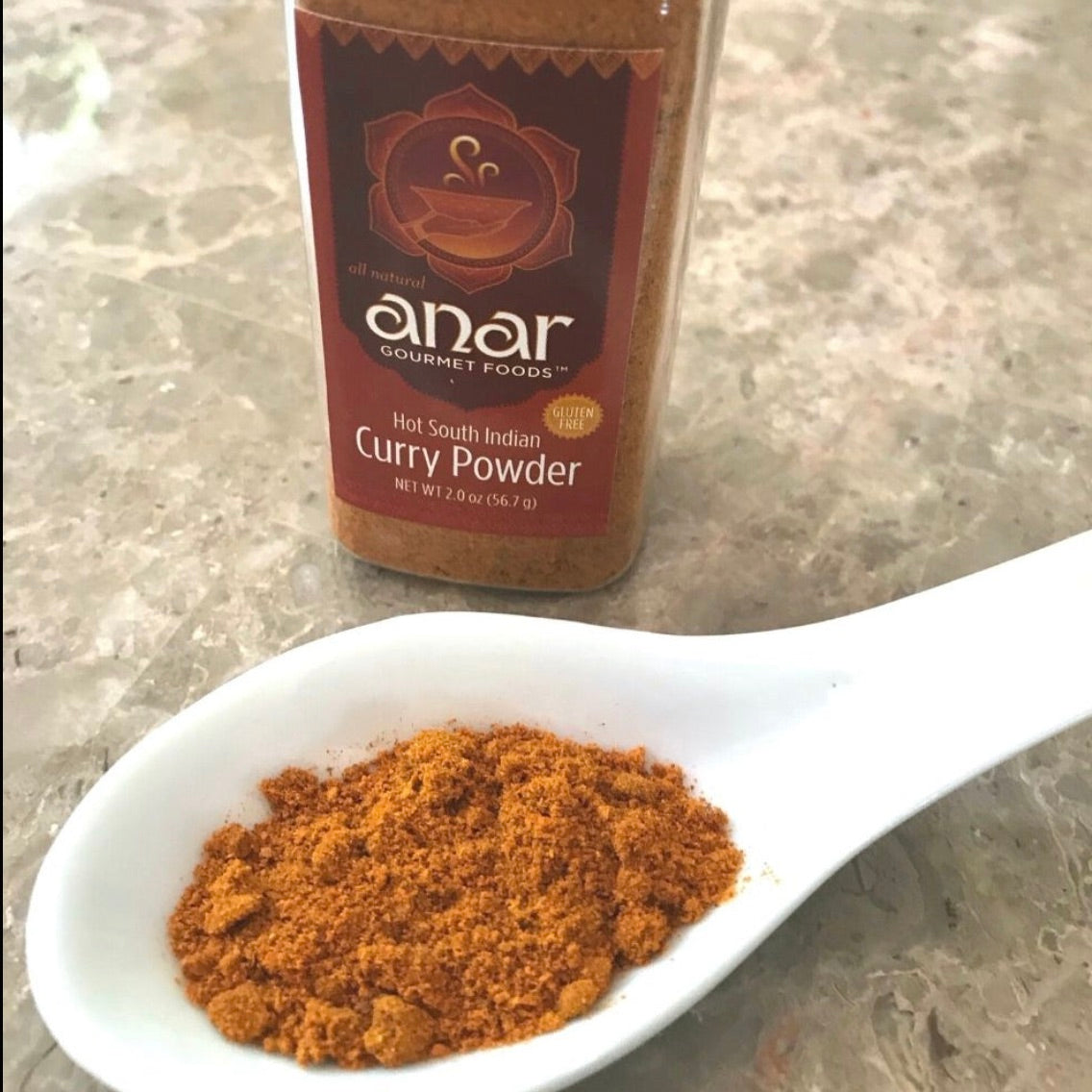 Anar Gourmet Foods all-natural South Indian hot curry powder — heaping teaspoon of curry powder beside the bottle