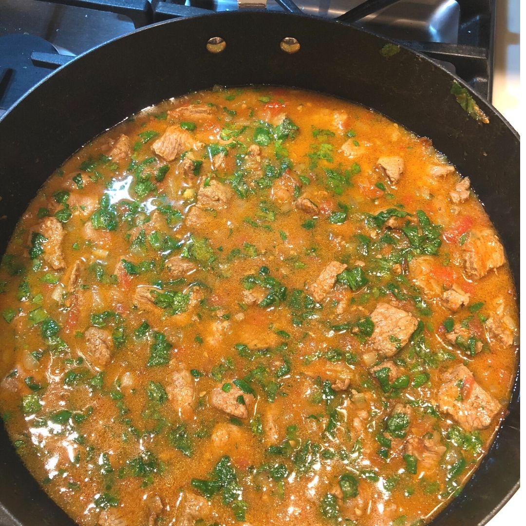 Anar Gourmet Foods all-natural, gluten-free lamb curry seasoning — lamb curry simmering in a skillet, garnished with cilantro