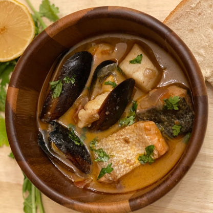 Anar Gourmet Foods all-natural, gluten-free seafood curry with mussels and fish, served in a wooden bowl with lemon and bread