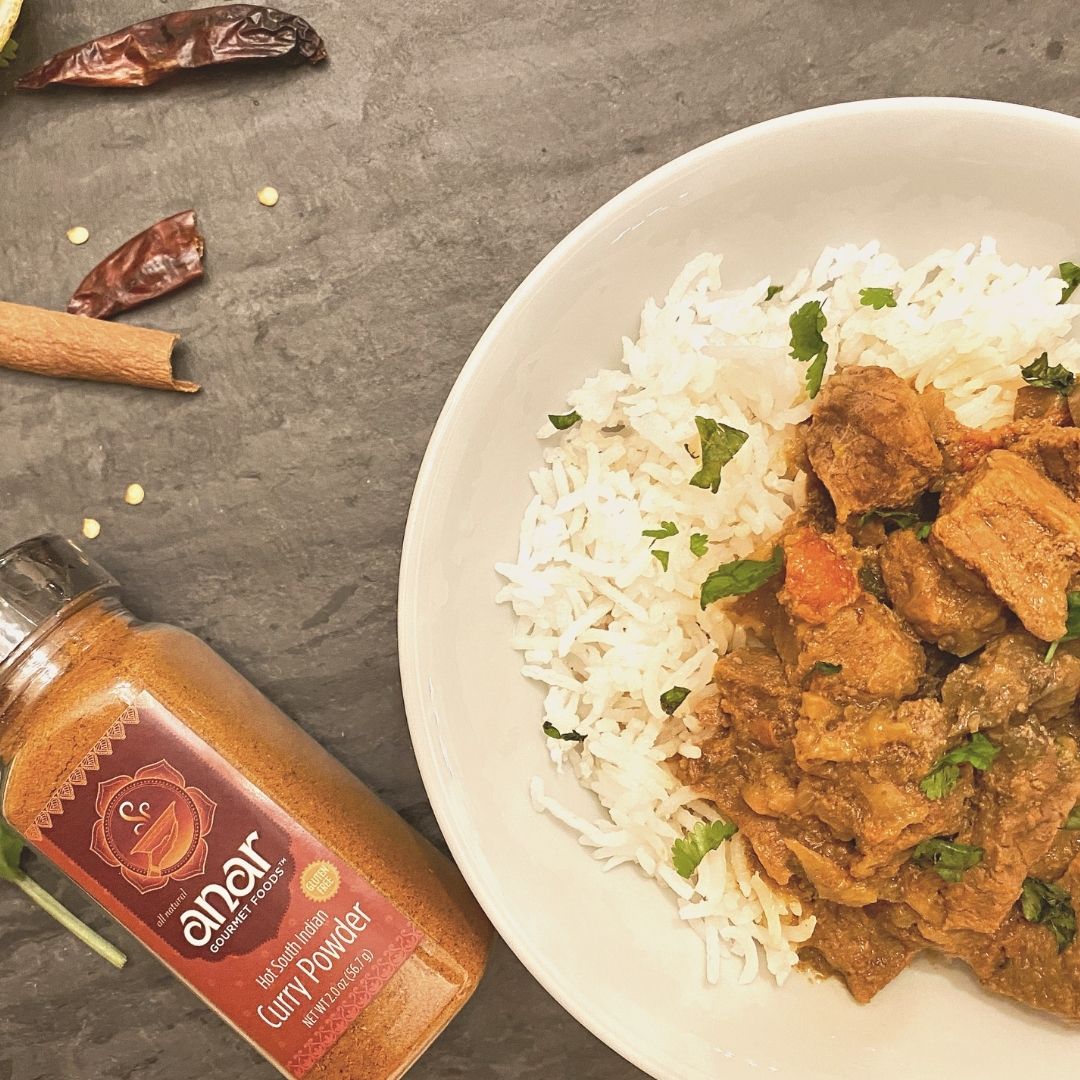 Anar Gourmet Foods all-natural South Indian hot curry powder — curry over rice with bottle, styled with cinnamon and dried chilies