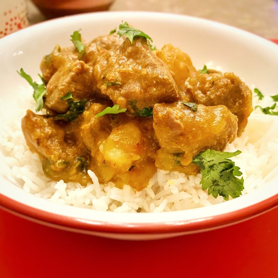 Anar Gourmet Foods all-natural, gluten-free spicy beef curry with potatoes, served over rice in a red bowl